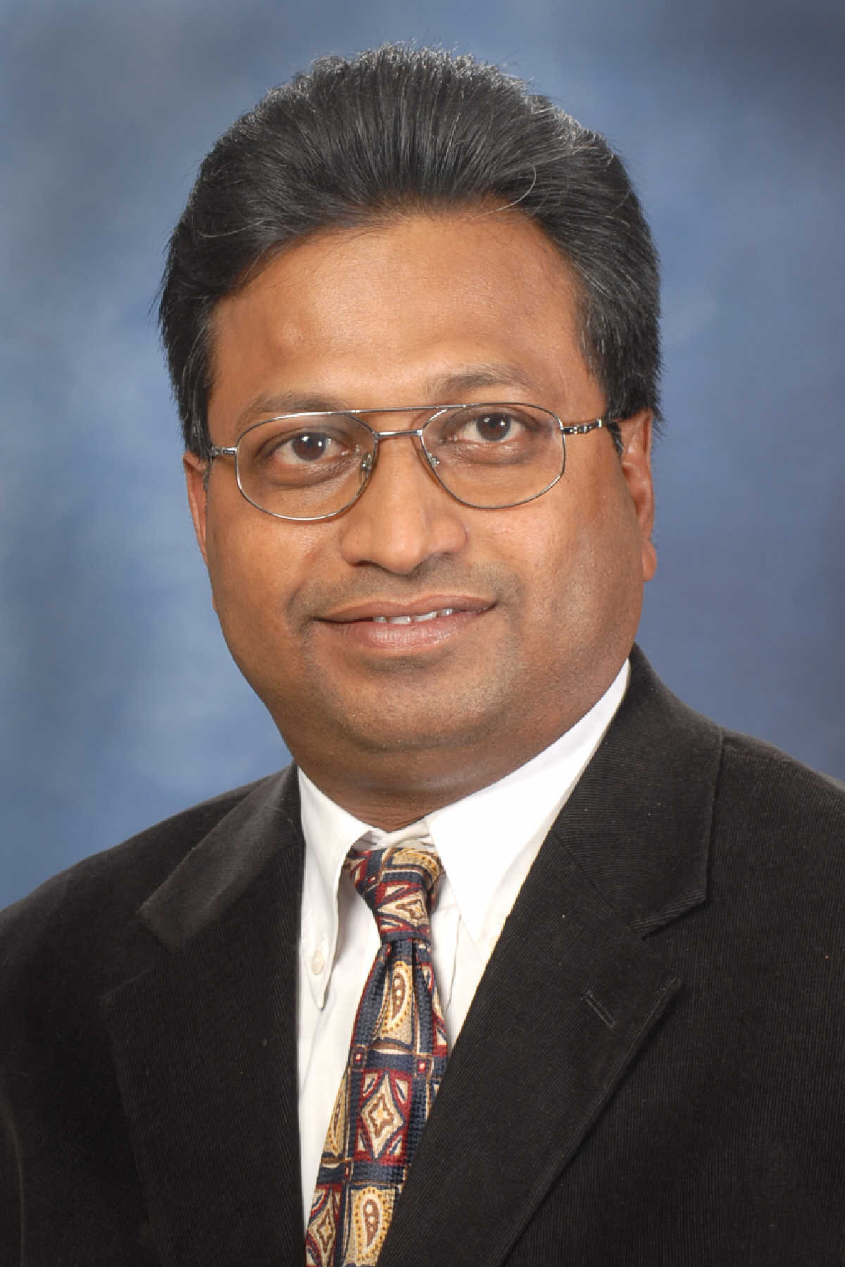 Praveen Katta, a prominent broker in the Louisville, Kentucky real estate market, stands confidently in a professional photograph.